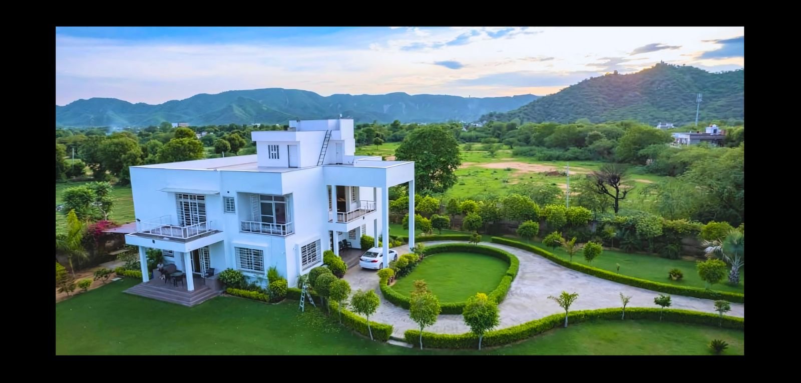 Aerial shot of a villa with the Aravalli hills behind